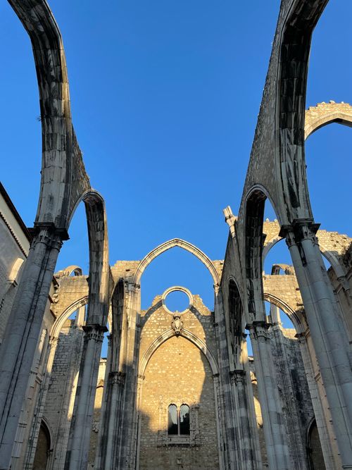 Free Gothic arches of the Carmo Convent ruins in Lisbon under a clear blue sky. Stock Photo