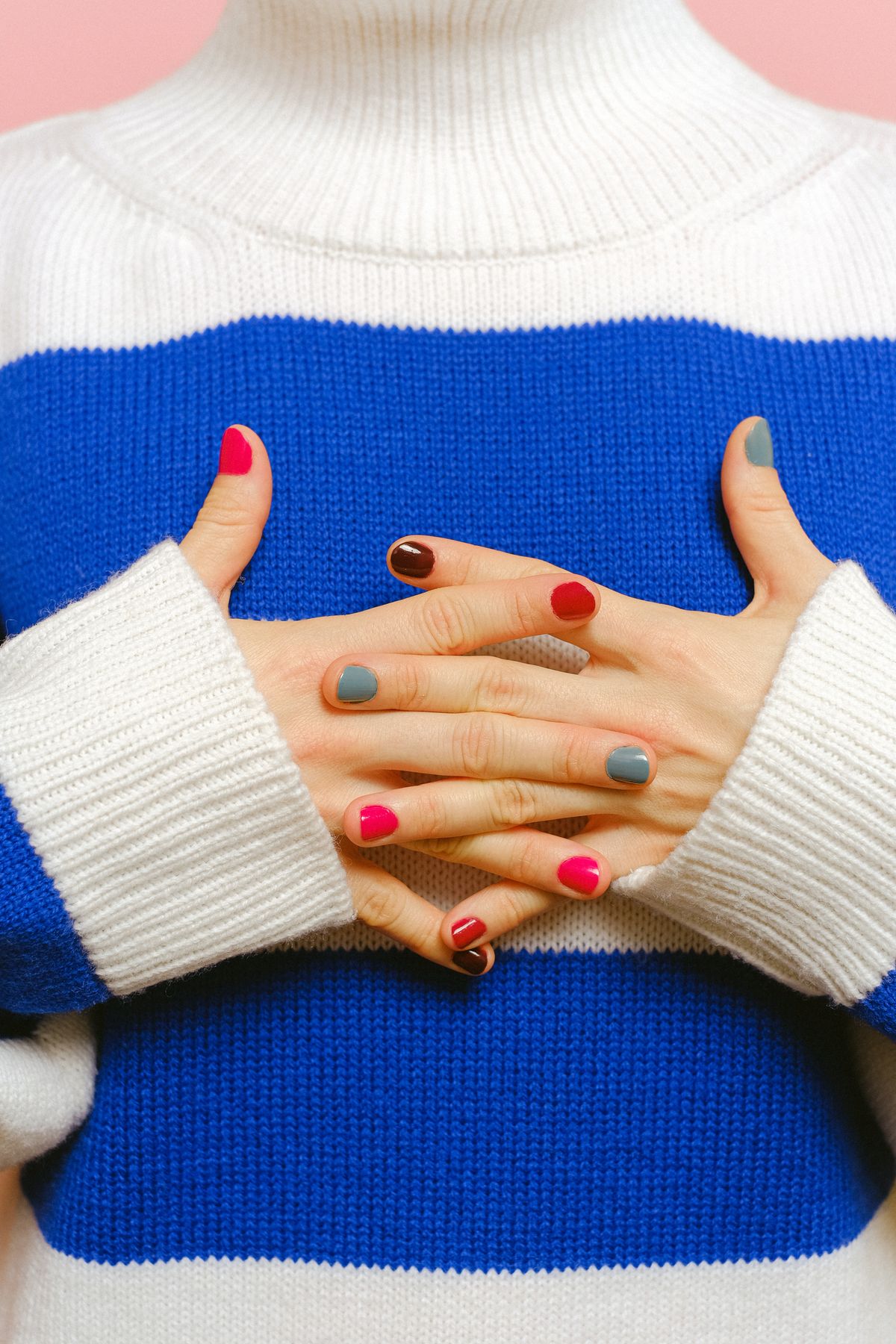 Close-up of beautifully manicured nails with vibrant nail polish colors, paired with a stylish striped sweater.
