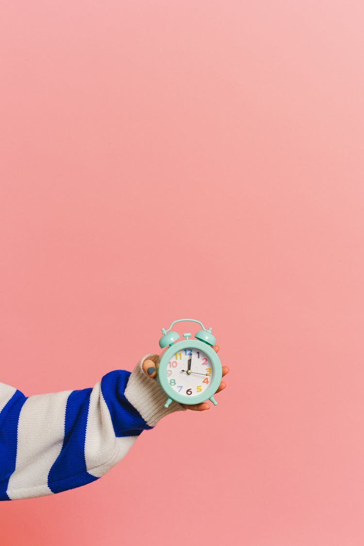 Photo Of A Hand Keeping Clock On Red Background