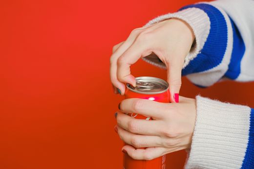 Hands opening a chilled can on a red backdrop — photo by Anna Shvets on Pexels