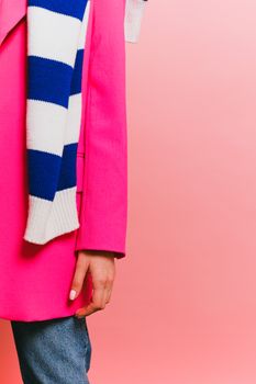 A stylish woman's fashion featuring a pink coat and blue striped scarf, ideal for winter style inspiration.