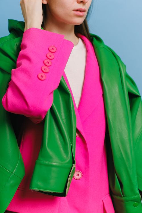 Free Fashionable woman wearing a vibrant pink blazer and green jacket, exuding modern style. Stock Photo