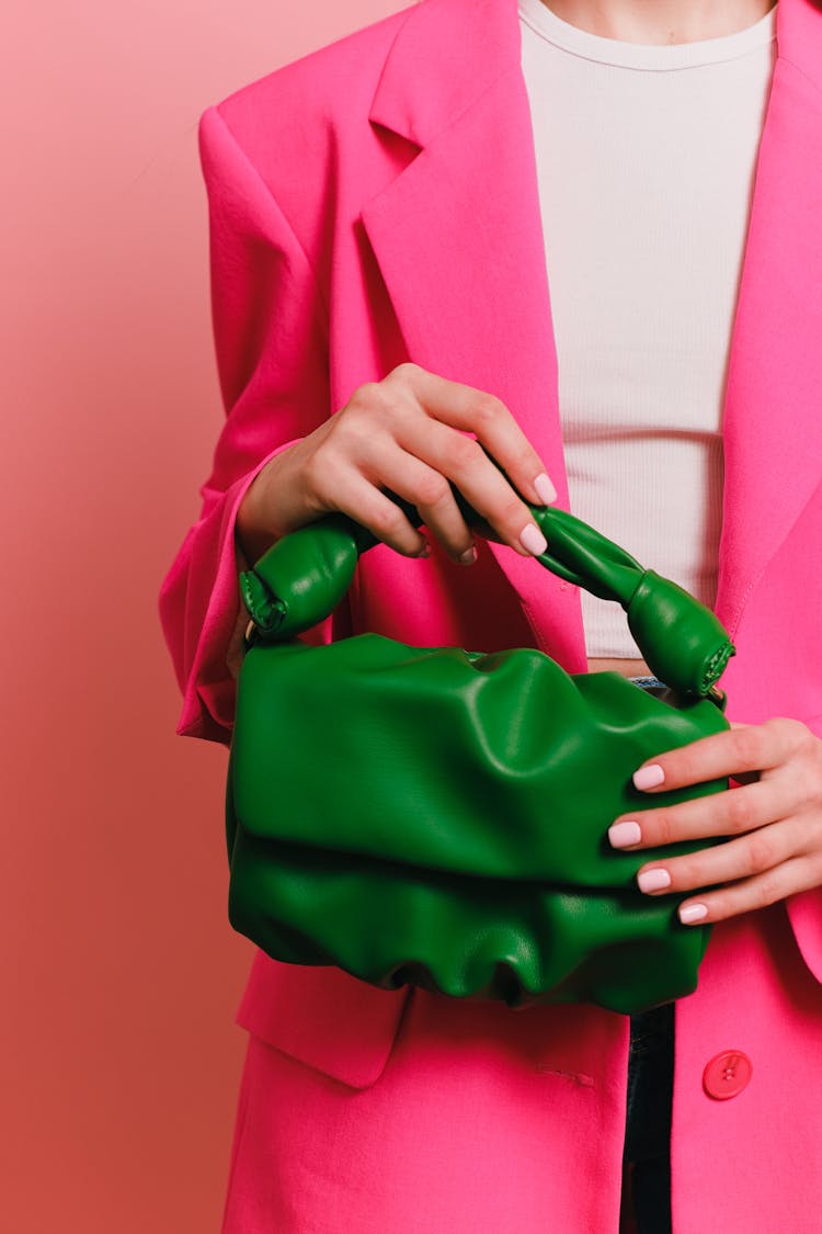 Woman Wearing Pink Blazer Holding A Green Handbag