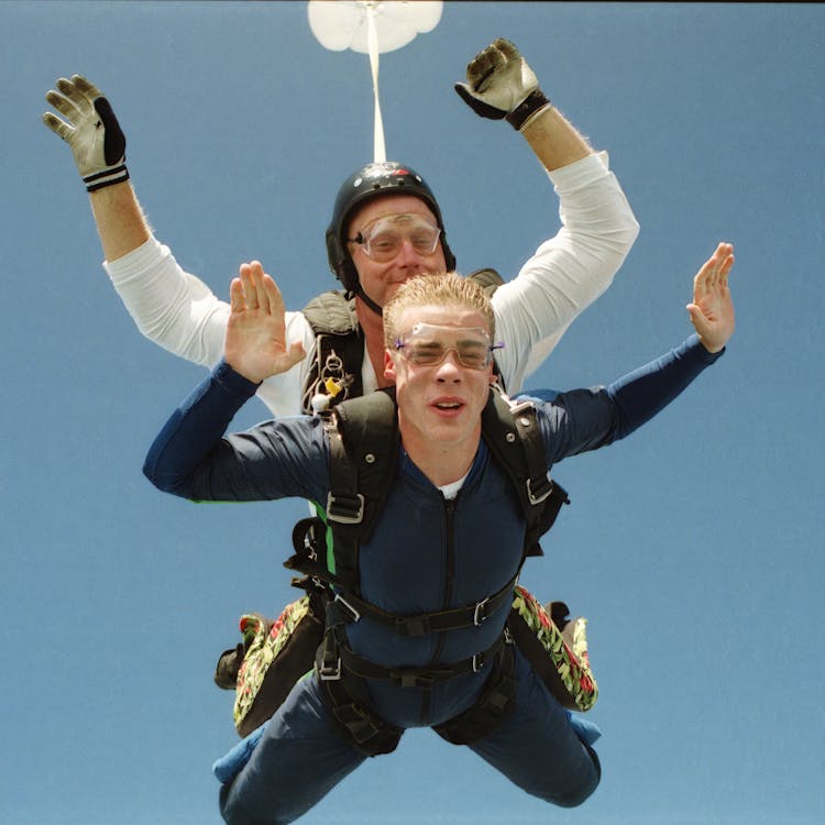 Two Men Jumping Together With Parachute