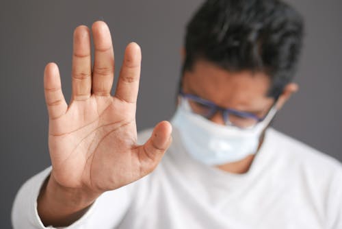 Man in Face Mask Doing Stop Sign Signal