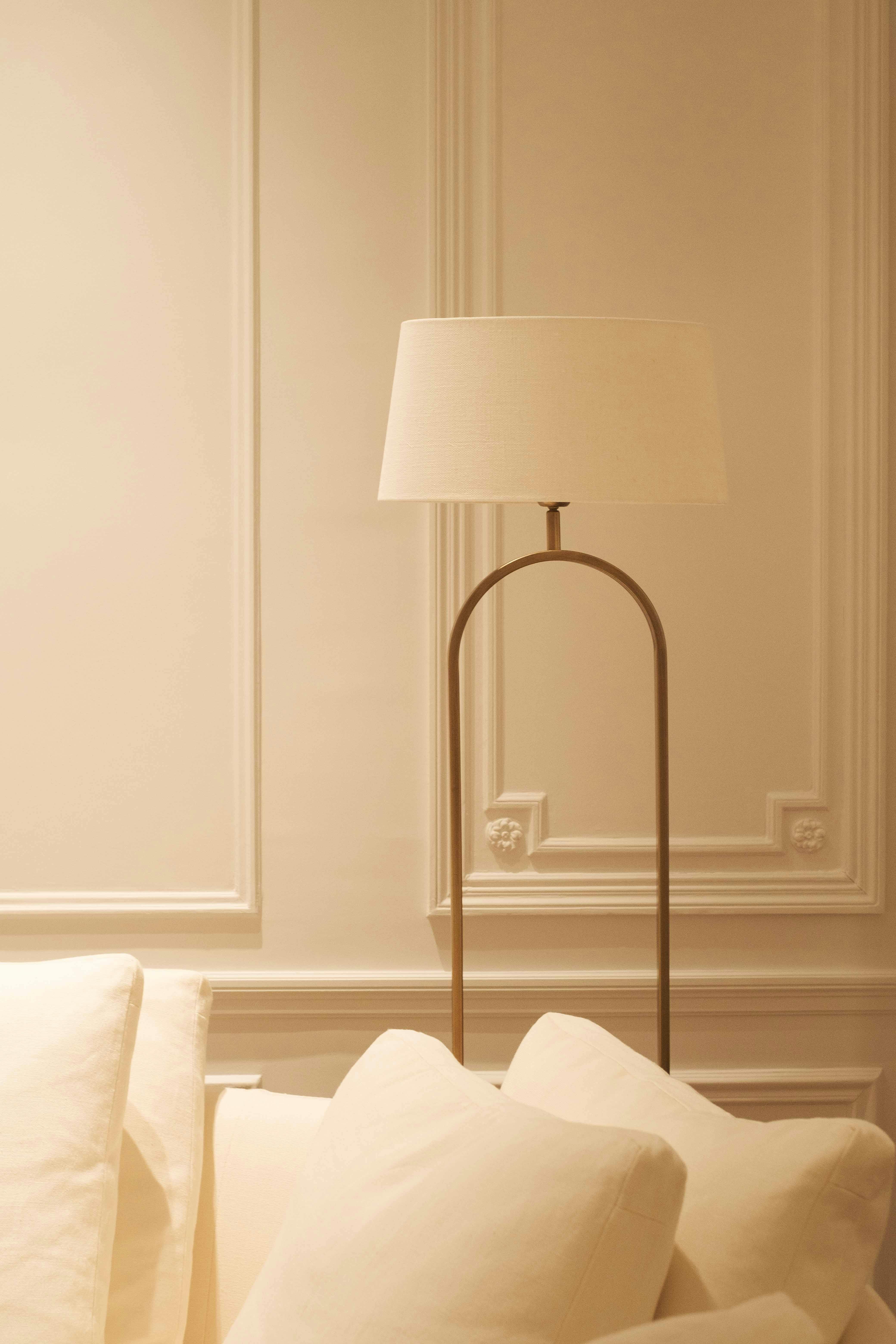 A minimalist interior room with a modern lamp and white pillows on a sofa.