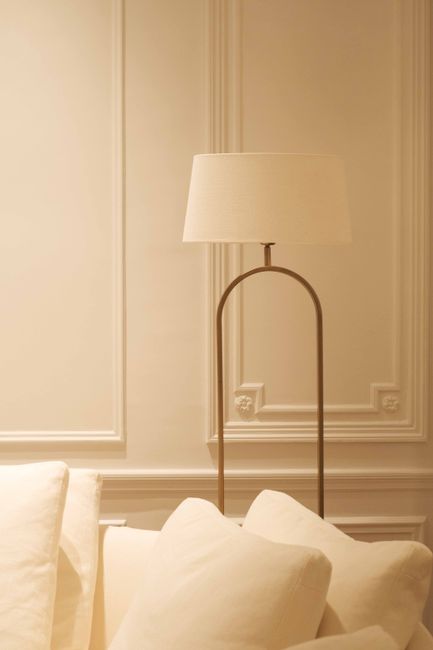 A minimalist interior room with a modern lamp and white pillows on a sofa.