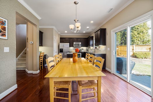 Bright and spacious kitchen dining area with a wooden table and chairs, showcasing a modern interior design.