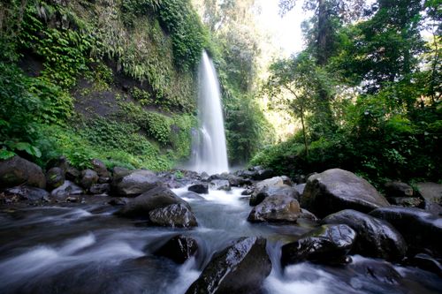 Free A beautiful waterfall cascades in West Nusa Tenggara, surrounded by lush greenery and rocks. Stock Photo