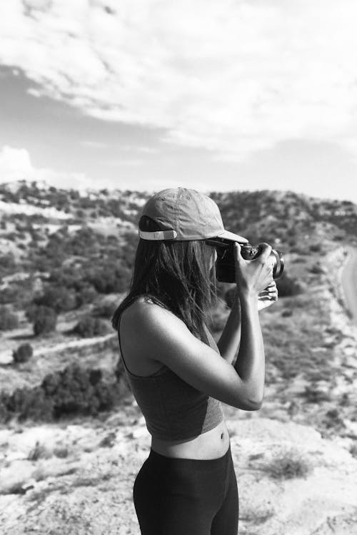 A Woman in Tank Top Taking Photos using a Camera