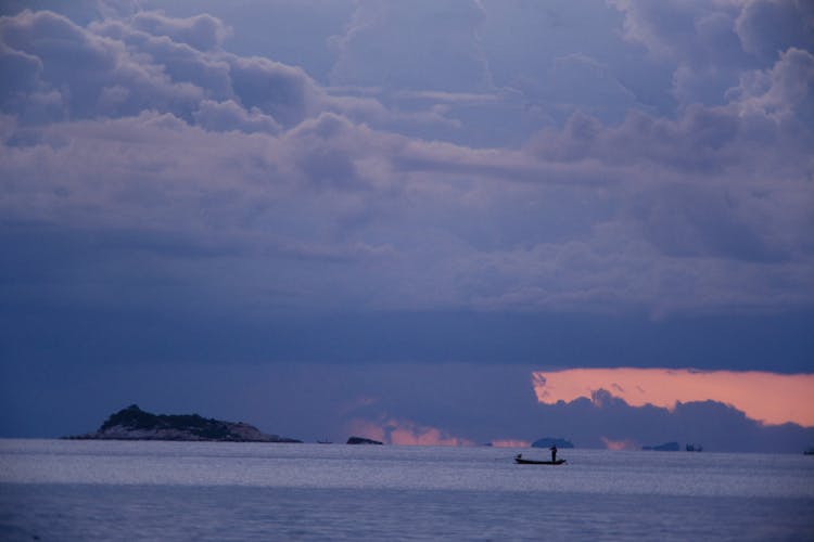 Boat In Sea Under Storm Clouds At Sunset