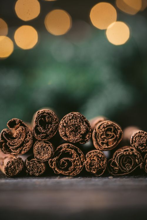 Free Artistic close-up of cinnamon sticks with festive bokeh lights, perfect for holiday themes. Stock Photo