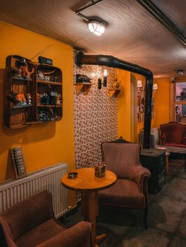 Warm and inviting vintage room with armchairs, wood stove, and decorative shelves.