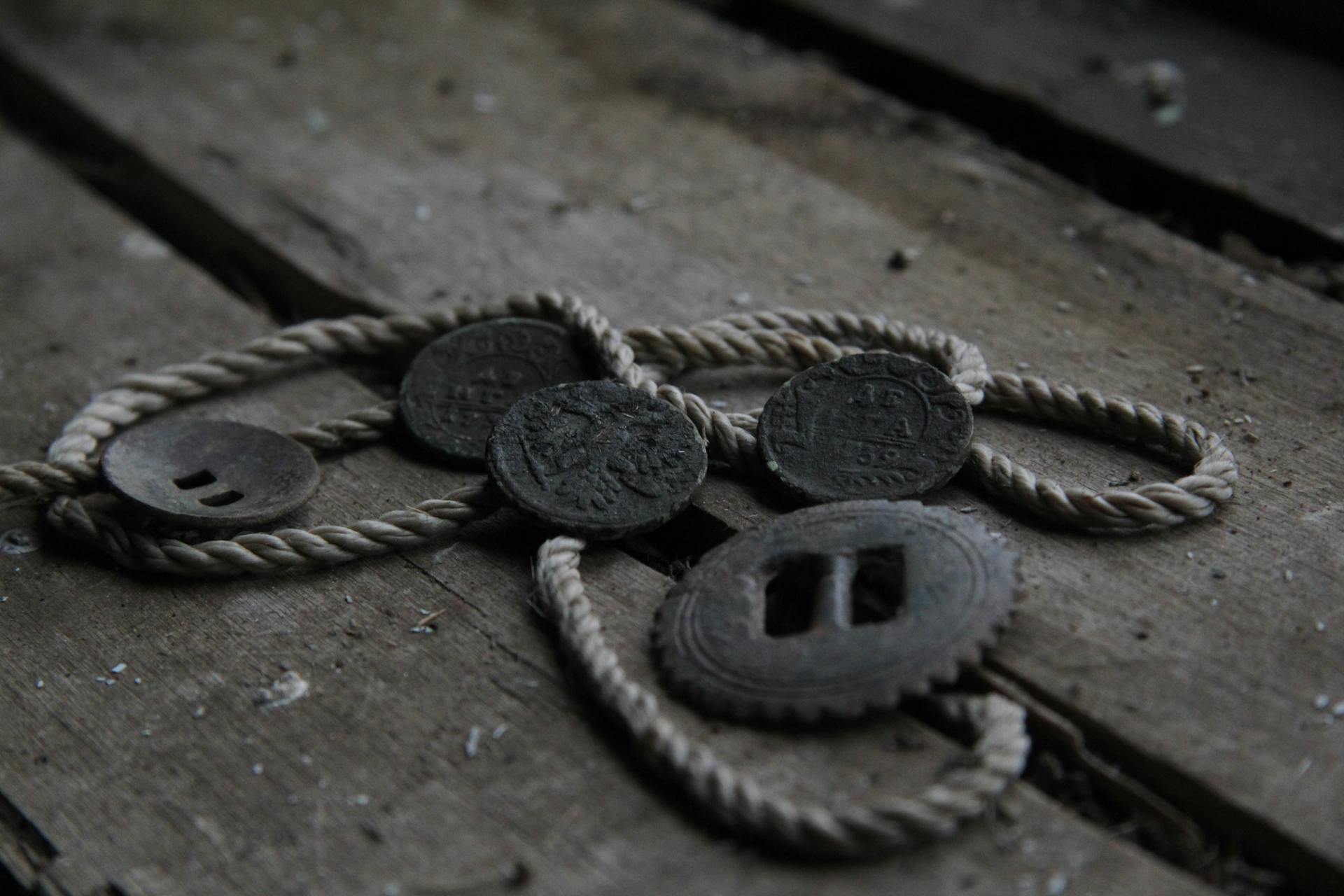 Close-up of vintage coins and rope on old wooden planks, evoking a sense of history and nostalgia.