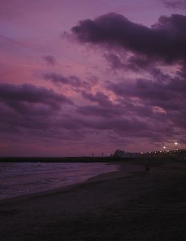 A stunning twilight view of Barcelona's beach with a vibrant pink sky and shimmering ocean.