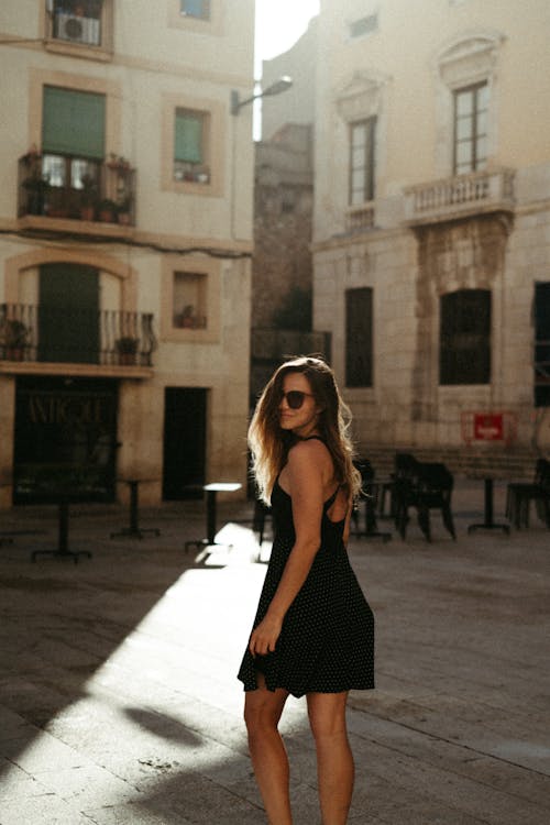 A Woman in Black Dress Standing on the Street