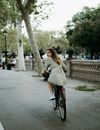 Woman in White Long Sleeve Shirt Riding on Bicycle
