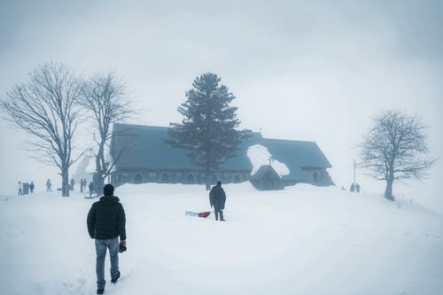 Free A peaceful winter scene featuring a church surrounded by snow and trees. Stock Photo