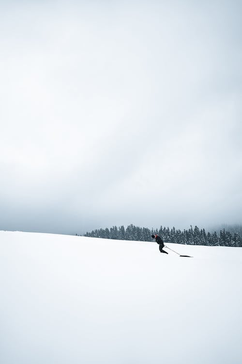 Person in Black Jacket and Black Pants Walking on Snow Covered Ground