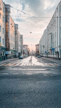 Empty urban street scene framed by tall buildings with clear road markings and a pedestrian lane.