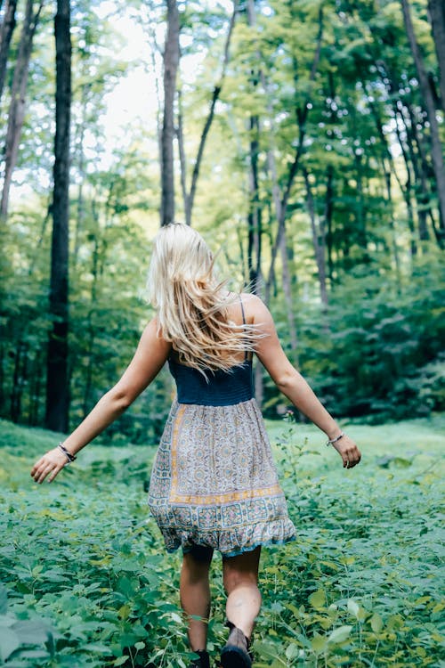 Free Blonde Woman Walking Through Green Forest Stock Photo