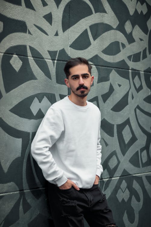 Man in a White Long Sleeve Shirt Posing with His Hands in His Pockets