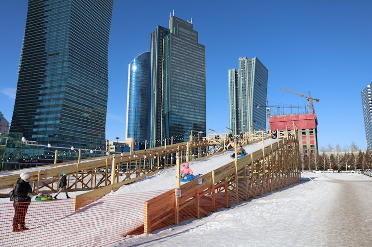 Children Sledding In A City