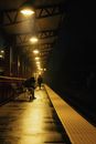 Man and Woman Sitting on Chair on Train Station during Night Time