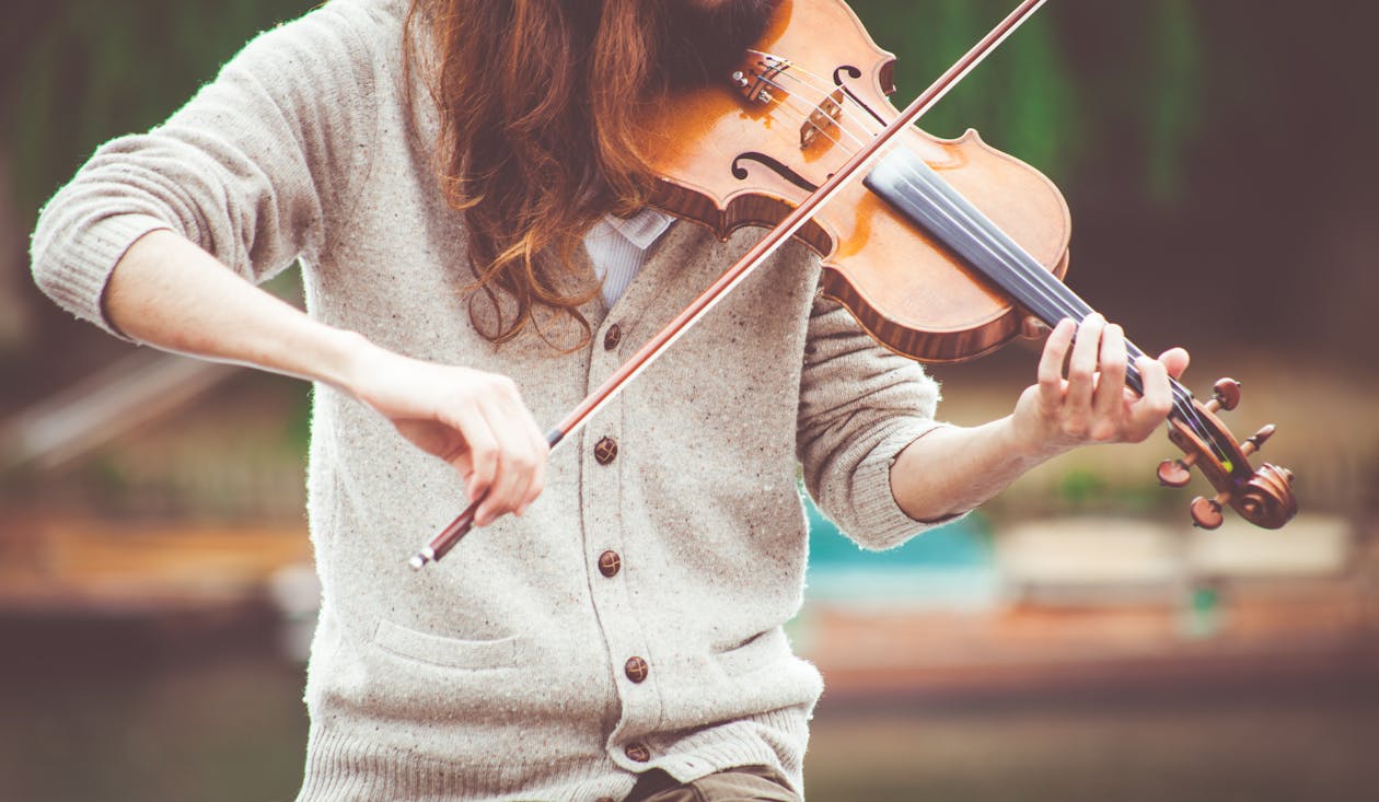 낮 동안 바이올린을 연주하는 회색 카디건에있는 여자