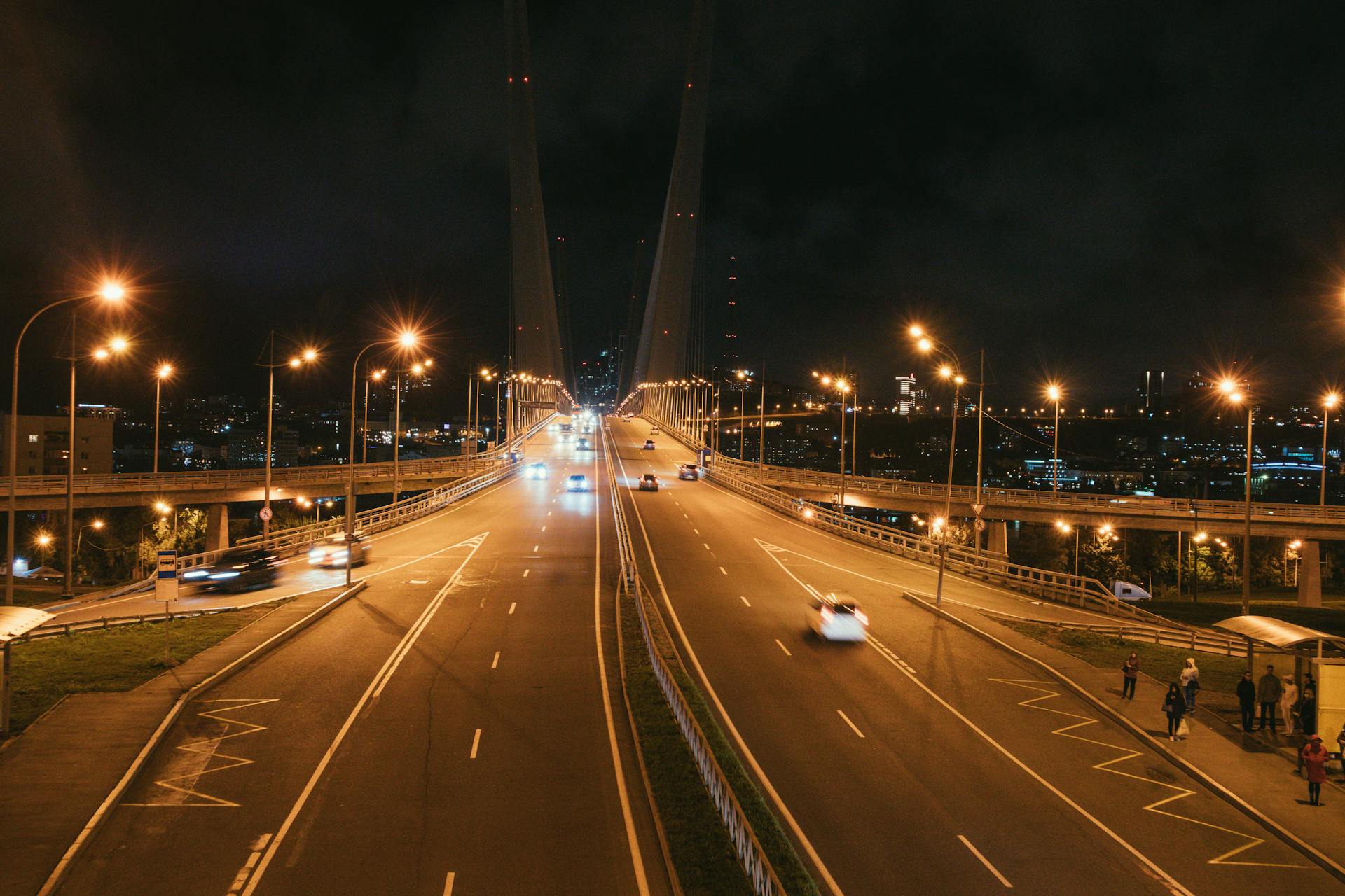 Aerial view of cars on the illuminated Golden Horn Bridge in Vladivostok at night.