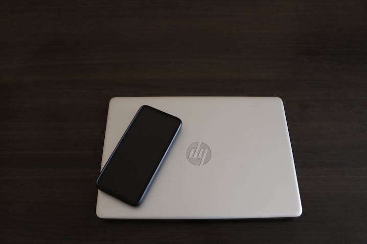 Close-Up Shot Of A Smartphone On Top Of A HP Laptop