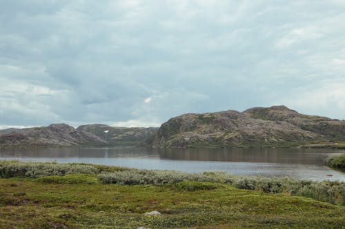 Green Grass Field Near Lake and Mountains