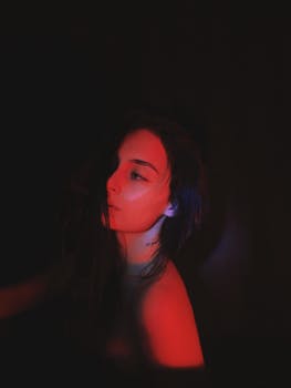 A dramatic and artistic portrait of a woman illuminated by red light.