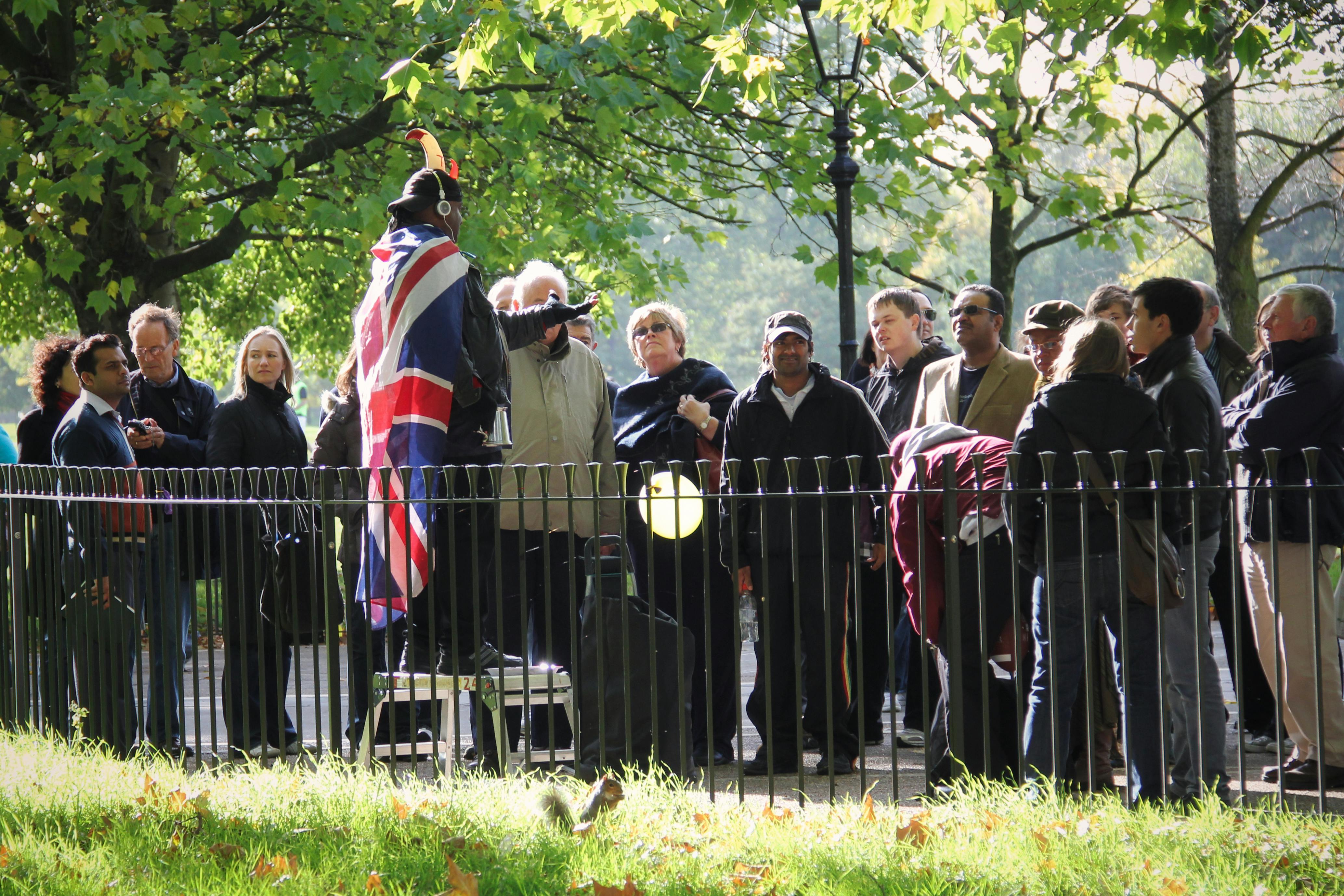 Free A lively gathering at Hyde Park's Speakers' Corner with a speaker draped in the Union Jack flag. Stock Photo