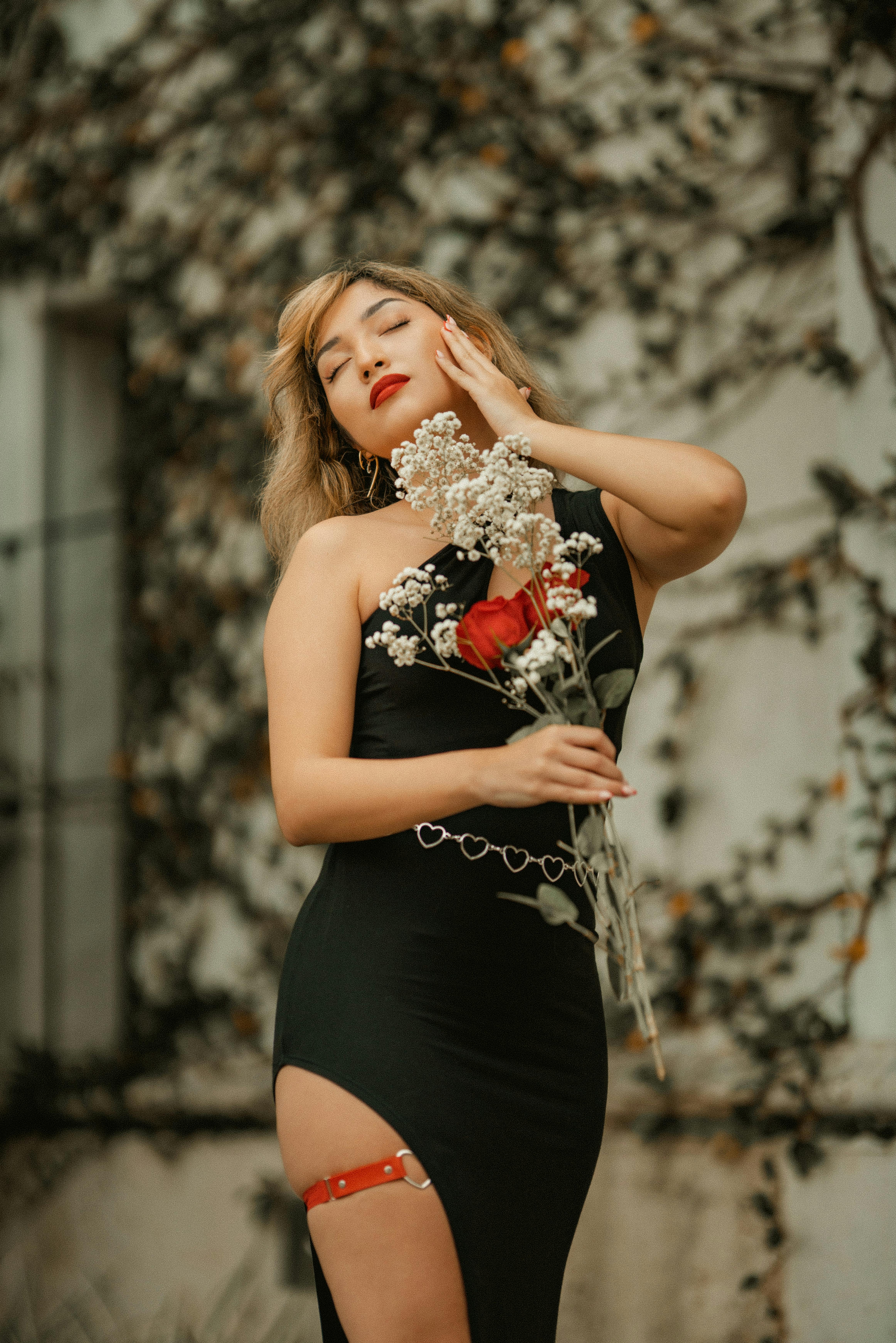 一位穿着黑色连衣裙搭配红玫瑰的优雅女士，在户外散发出精致的气质