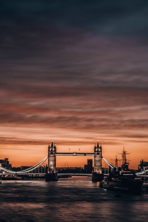 Free Breathtaking view of Tower Bridge in London at sunset with vibrant sky and calm river reflection. Stock Photo