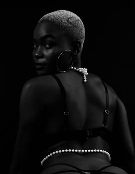 Stunning monochrome portrait of a woman with short hair and pearl necklace in a contemplative pose.