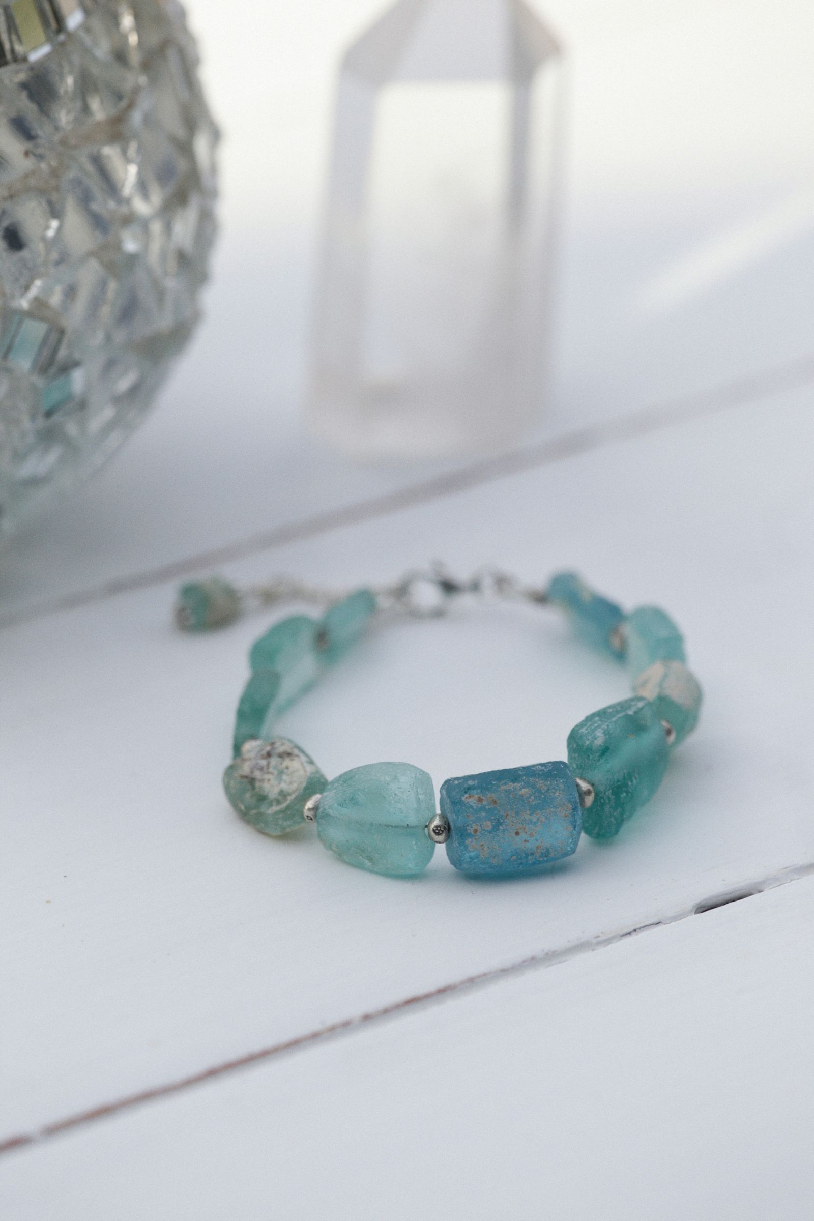 Turquoise beaded crystal bracelet on a white wooden surface with soft natural light
