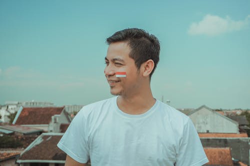 A Man in White T-shirt With a Sticker Flag on His Cheek