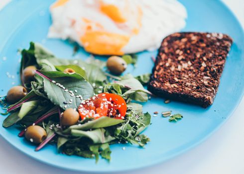 Delicious breakfast plate featuring eggs, salad, and toast on a vibrant blue plate.