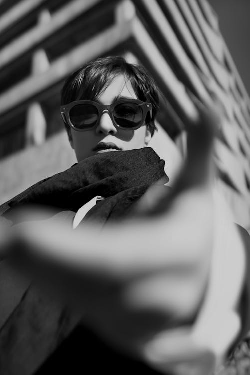 Grayscale Photo of a Woman with Sunglasses Reaching