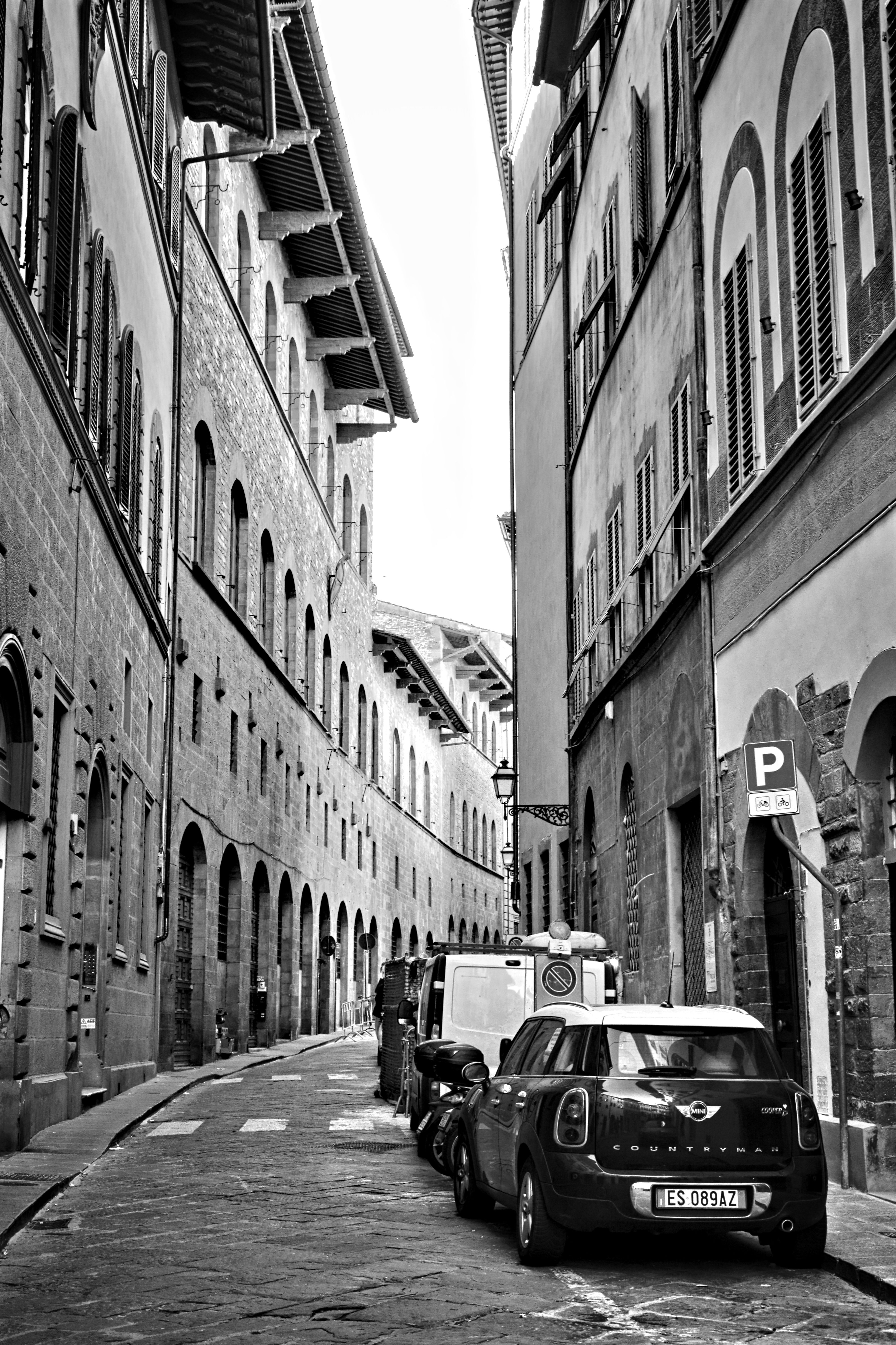 Black and white photo of city street with parked cars and historic architecture.