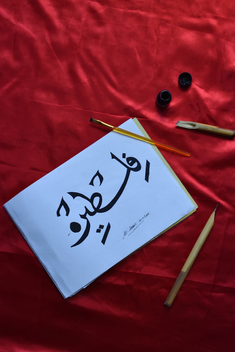 Persian Calligraphy And Tools On A Red Velvet Background