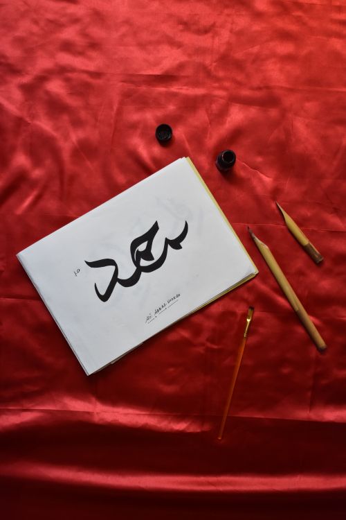 Free Persian calligraphy set on red velvet with brushes and paper. A concept of elegance and art. Stock Photo