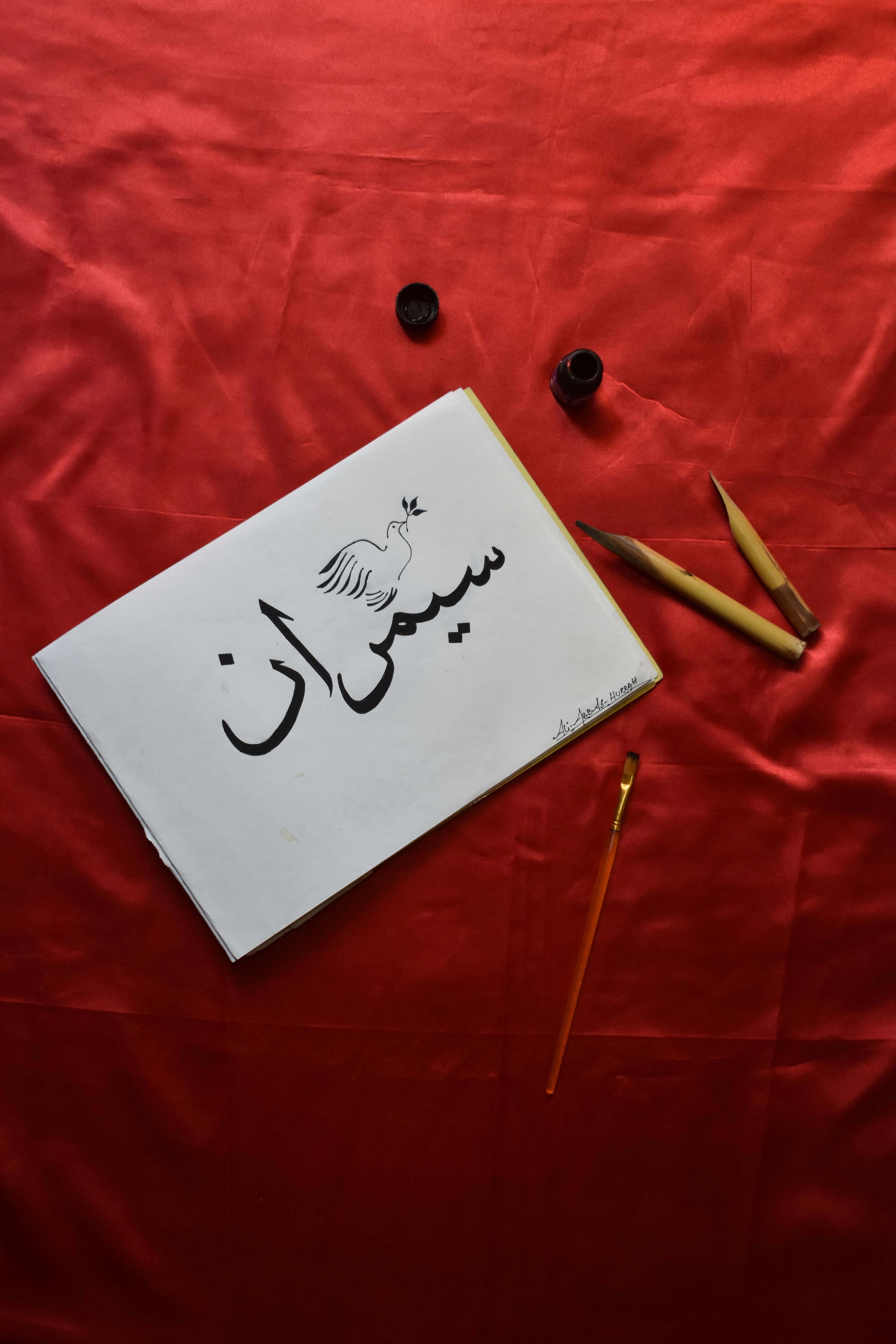 Elegant Persian calligraphy with art tools on red velvet, showcasing traditional writing techniques.