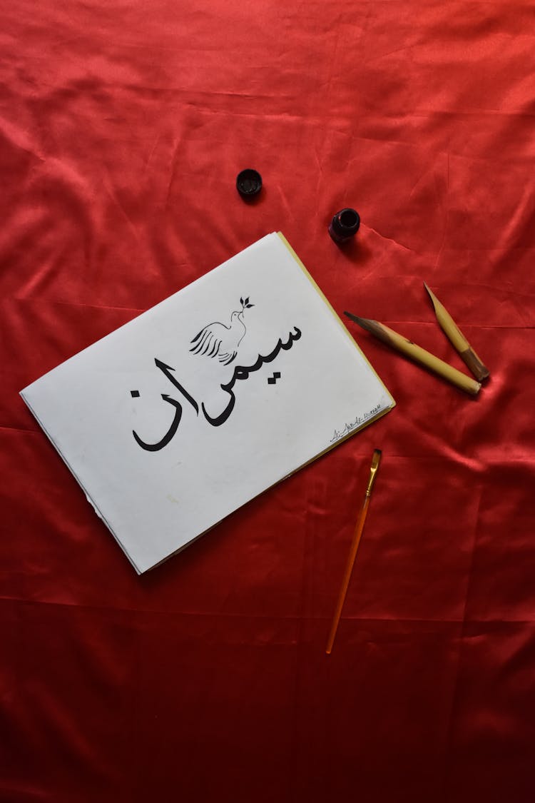 Persian Calligraphy And Tools On A Red Velvet Background