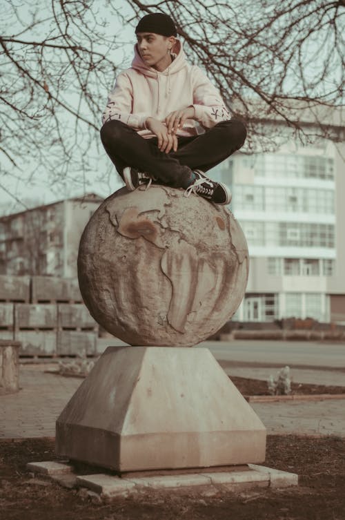 Photo of a Man Sitting on a Globe