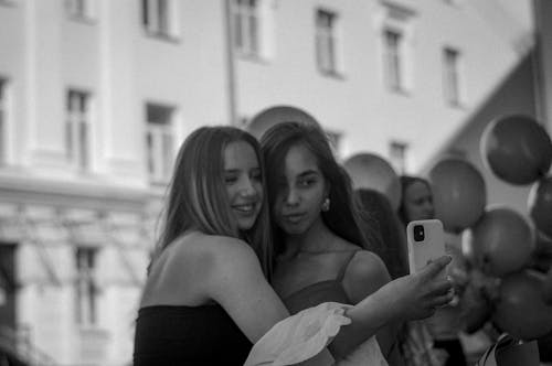 Grayscale Photo of a Girl Taking a Photo with Her Friend