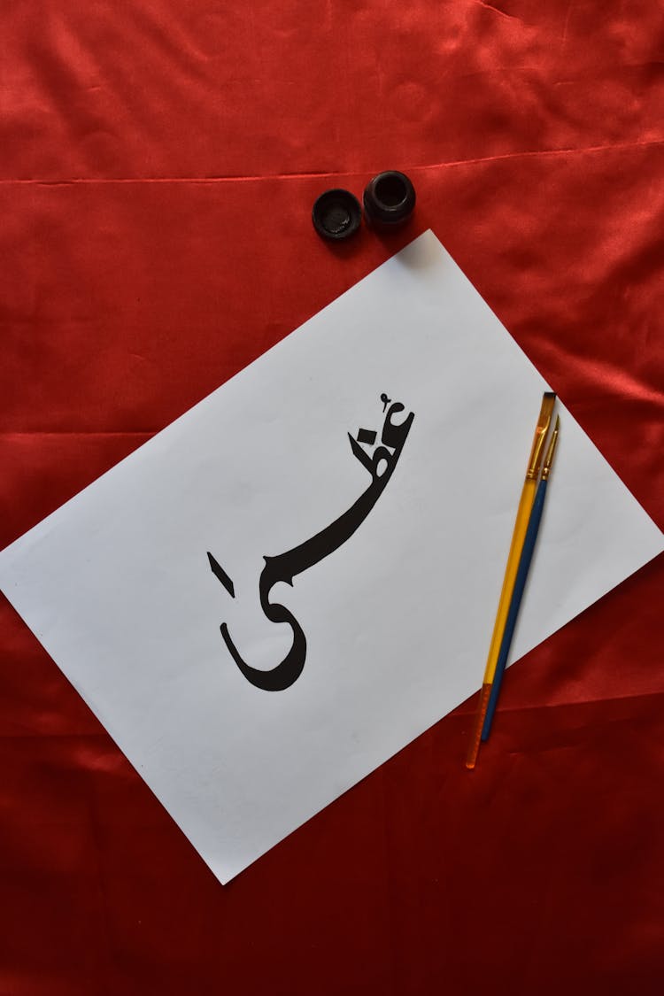 Persian Calligraphy And Tools On A Red Velvet Background