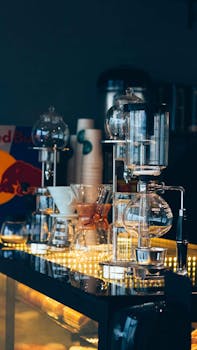 A stylish coffee brewing setup at a modern café featuring glass syphon coffee makers under warm lighting.